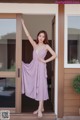 A woman standing in front of a door wearing a purple dress.