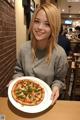 A woman holding a plate with a pizza on it.