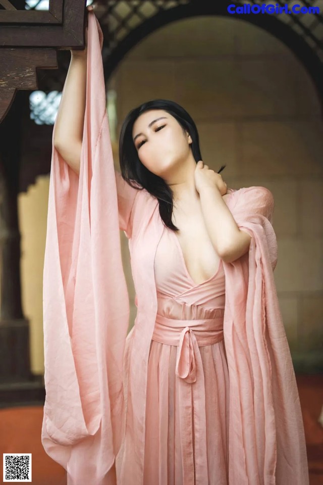 A woman in a pink dress is posing for a picture.