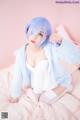 A woman with blue hair sitting on a bed.