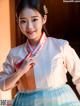 A woman in a blue and white hanbok is posing for a picture.