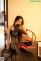 A woman sitting at a table with a pair of red high heels.