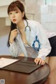 A woman sitting at a desk with a stethoscope on her neck.