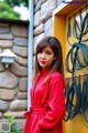 A woman in a red dress standing in front of a yellow wall.