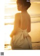 A woman in a white dress standing on the beach.