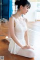 A woman in a white leotard sitting on the floor.