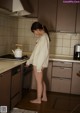 A woman standing in a kitchen next to a stove.