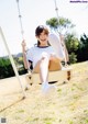 A woman sitting on a swing in a park.