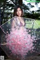 A woman holding a clear umbrella with pink flowers on it.